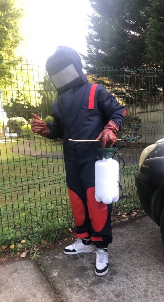 Technicien équipé d'une combinaison de protection et d'un pulvérisateur